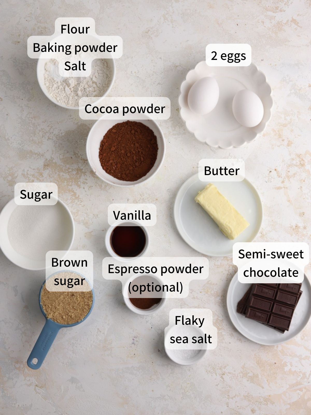 Labeled ingredients needed to make brownie crinkle cookies laid out on a table. 