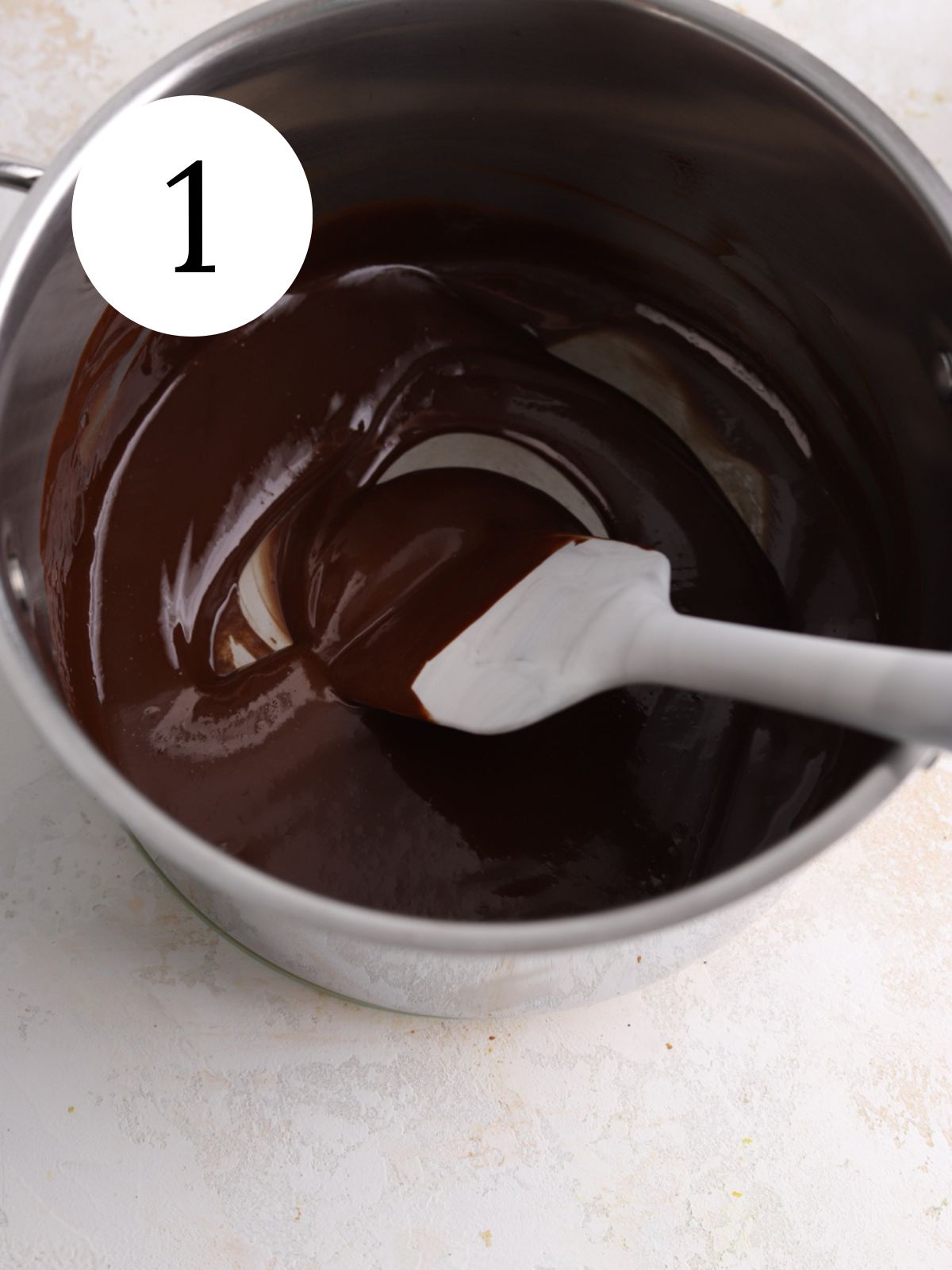 A saucepan with melted chocolate and a spatula. 