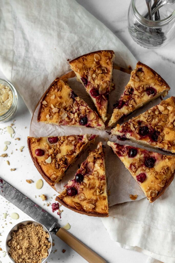 A cake with cranberries baked in it and almond slices on top. 