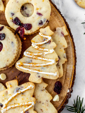 Cookies cut out in Christmas tree shapes on a wooden platter.