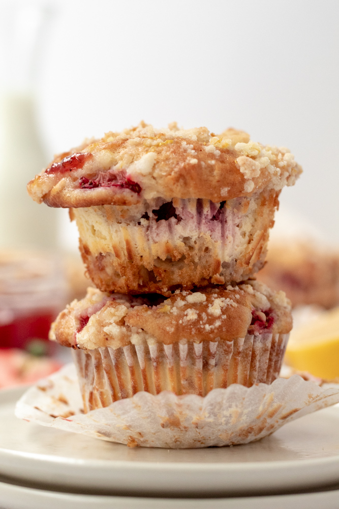 Two stacked muffins in a muffin liner studded with gooey berries baked inside. 