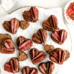 Heart shaped brownies with frosting piped on top on a white marble board.