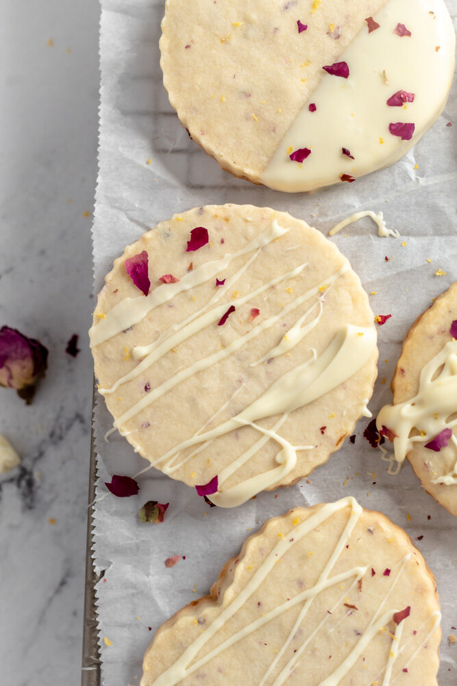 Cookies with lemon zest and crushed dried rose petals on top and drizzled with melted white chocolate. 