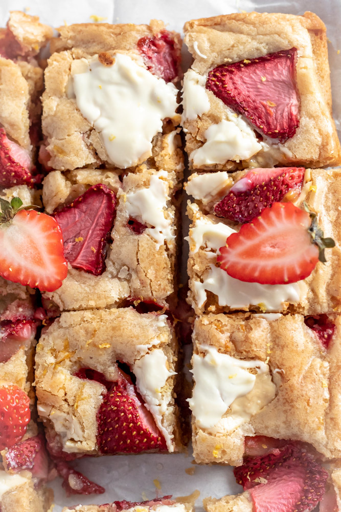 A beautiful batch of blondies topped with lemon zest, strawberries, and melted white chocolate. 