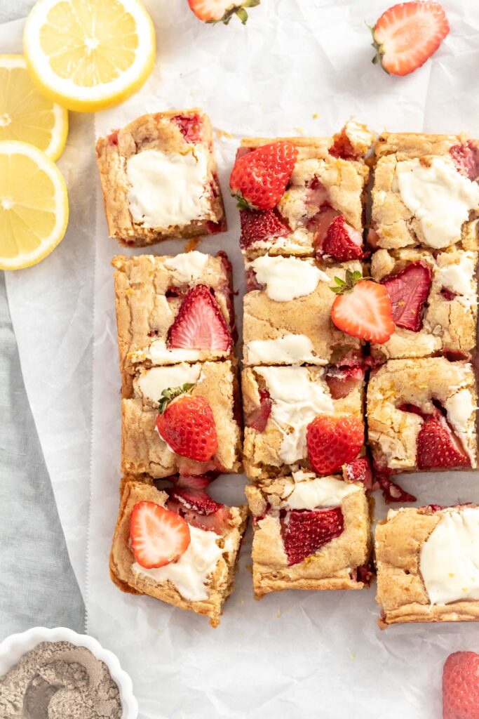 Golden brown blondies cut in squares topped with strawberries.