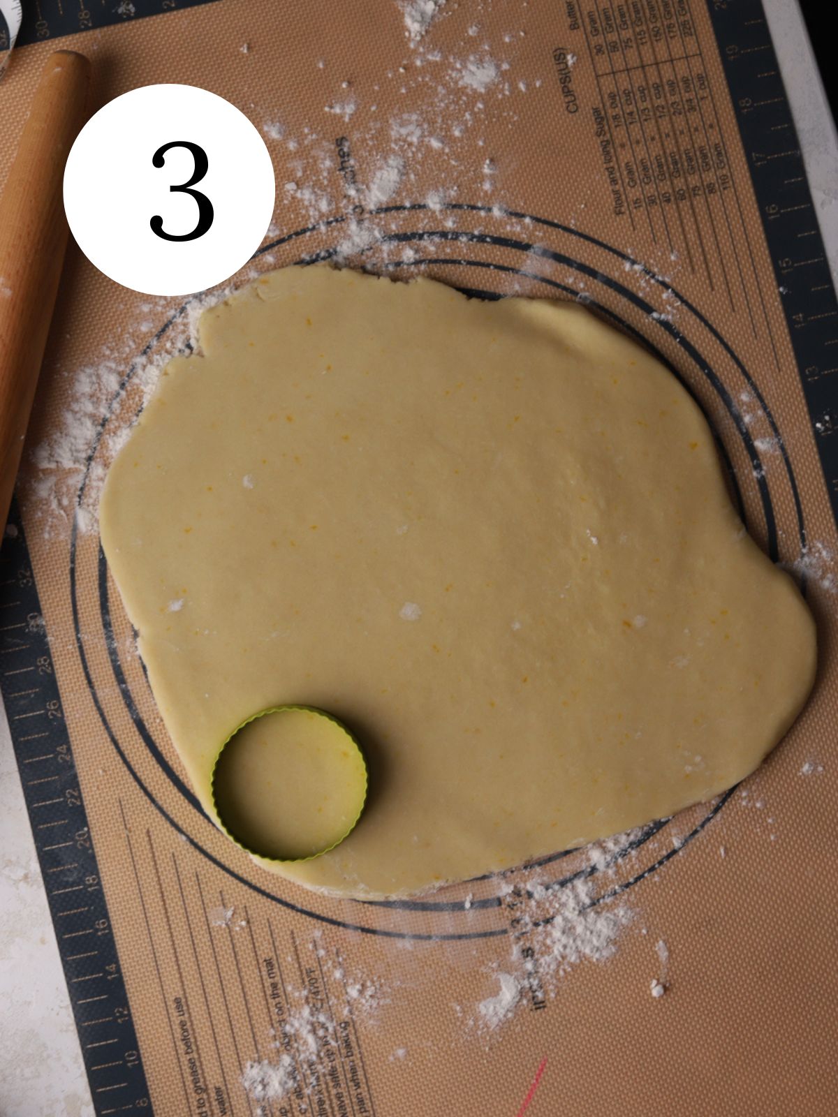 Rolled out cookie dough being cut with a round cookie cutter.