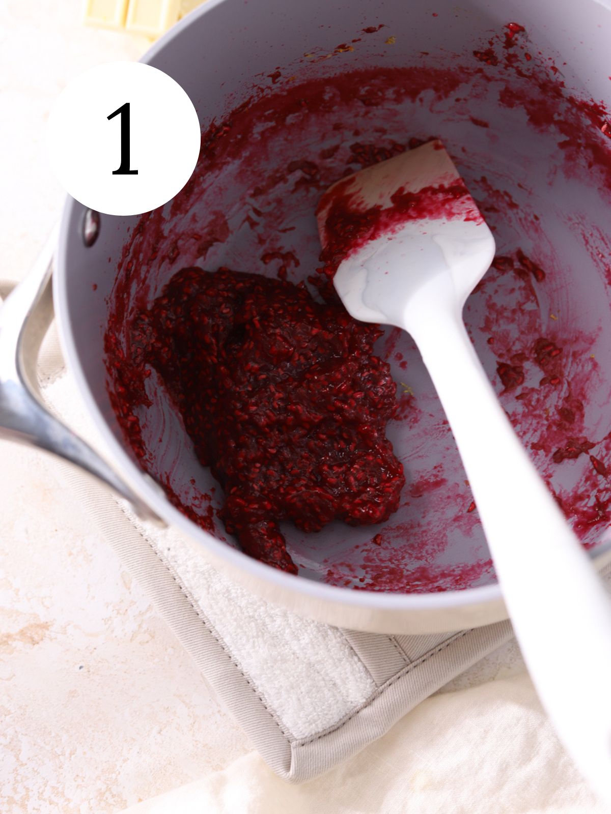 Raspberry jam in a pot with a spatula.