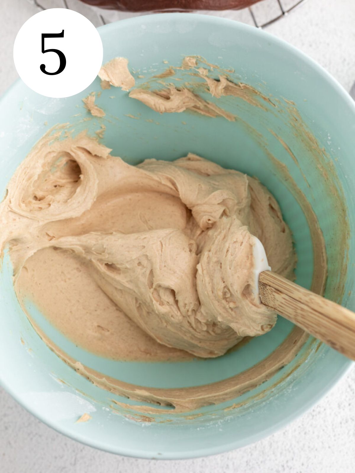 Peanut butter buttercream frosting in a bowl with a spatula.