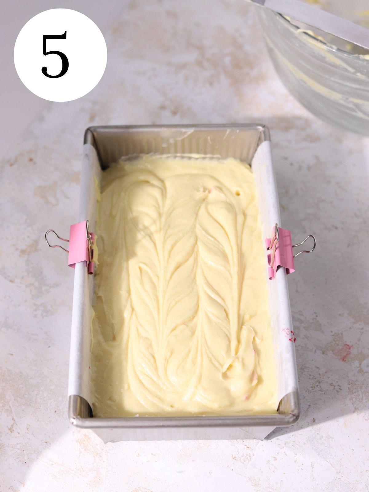 A loaf pan with vanilla cake batter in it.