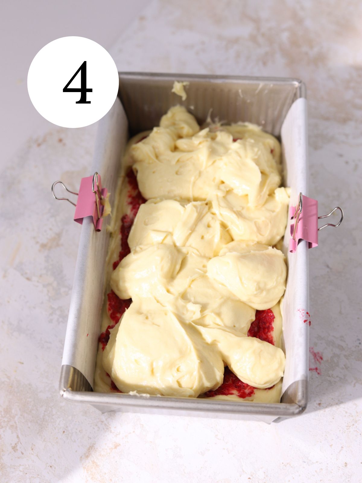 Vanilla cake batter added to a loaf pan lined with parchment paper.