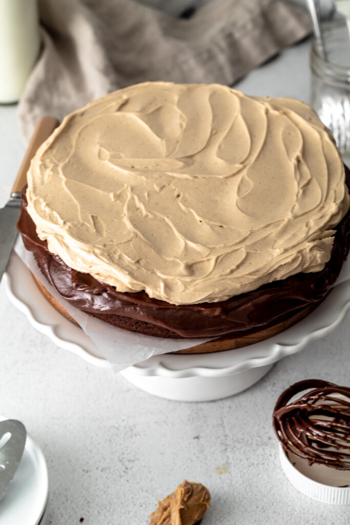 An overhead of a chocolate cake with peanut butter frosting and a whisk nearby.