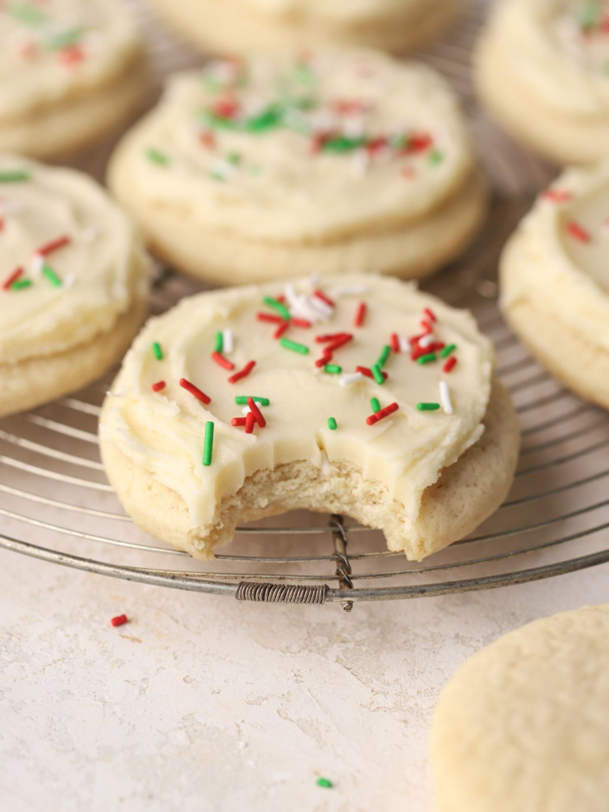 Sugar cookies on a rack with frosting and sprinkles. 