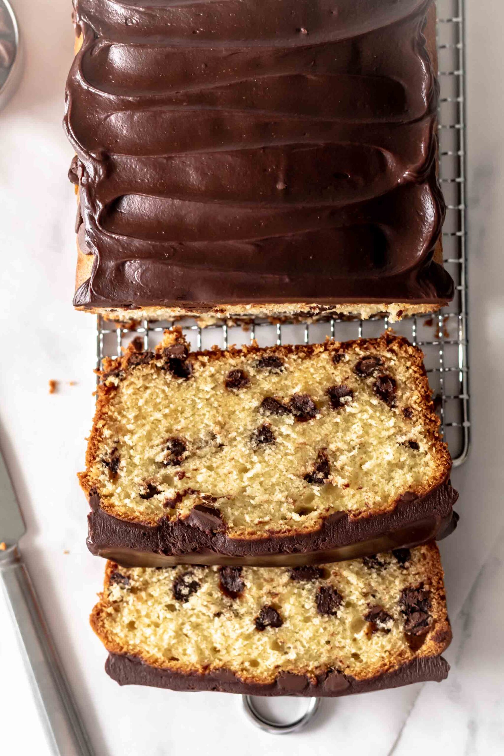 A loaf cake packed with chocolate chips and frosted with chocolate ganache. 