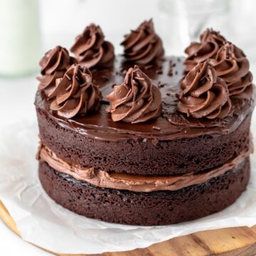 A mini two layer chocolate cake topped with ganache.