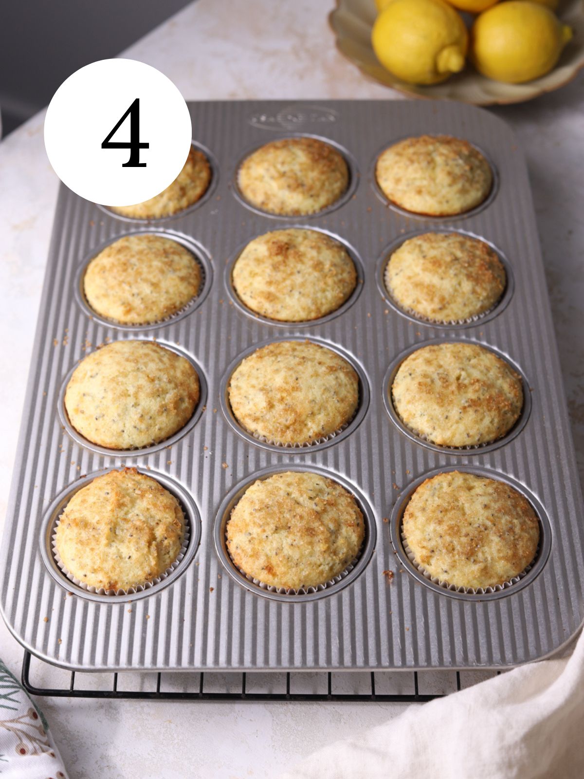 A muffin pan with lemon chia muffins next to a bowl with lemons.