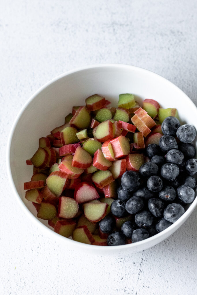 A white bowl with chopped rhubarb and blueberries in it. 