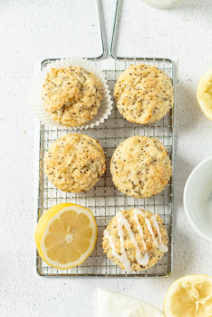 Five lemon muffins on a rack lemon halves next to them. 