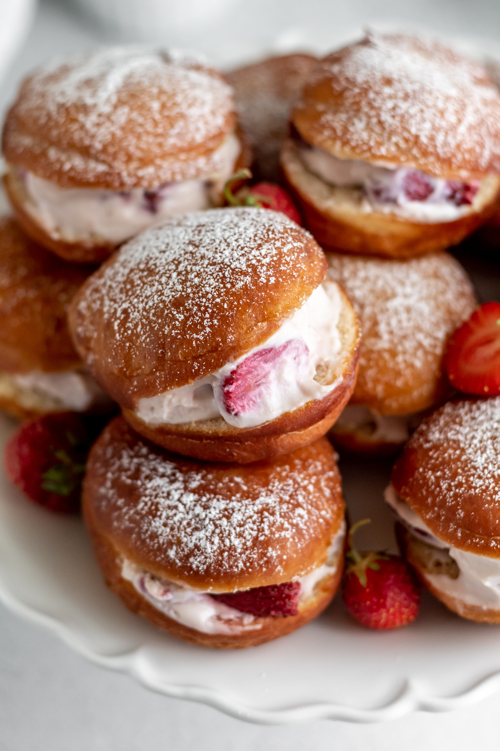 Doughnuts filled with cream and strawberries and dusted with powdered sugar on top. 