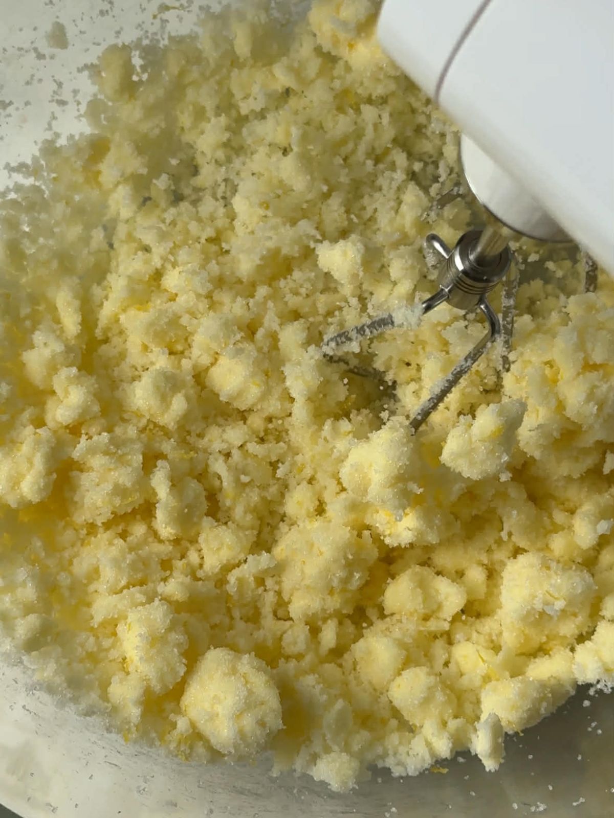 Butter and sugar being mixed with an electric mixer.