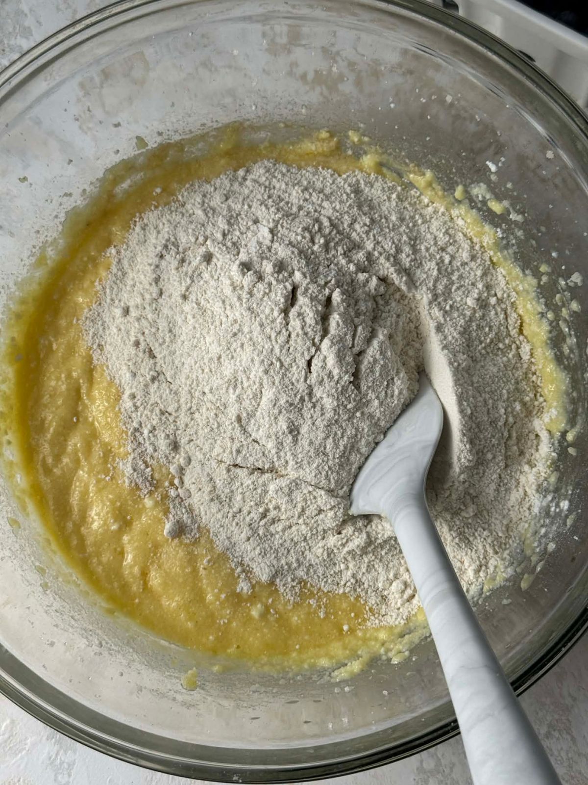 Stirring flour into cake batter in a bowl.