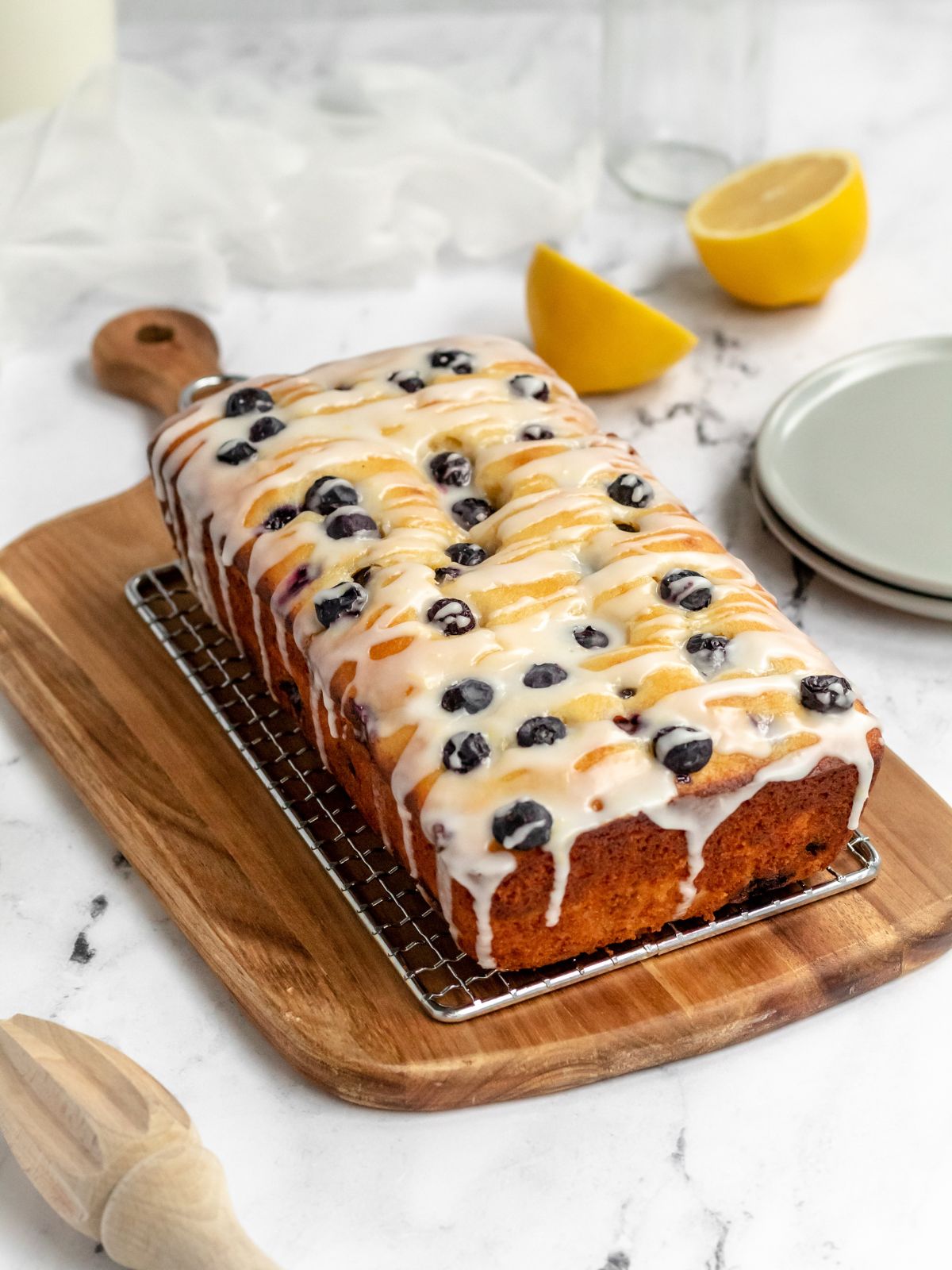 Blueberry loaf cake drizzled with icing on a rack.