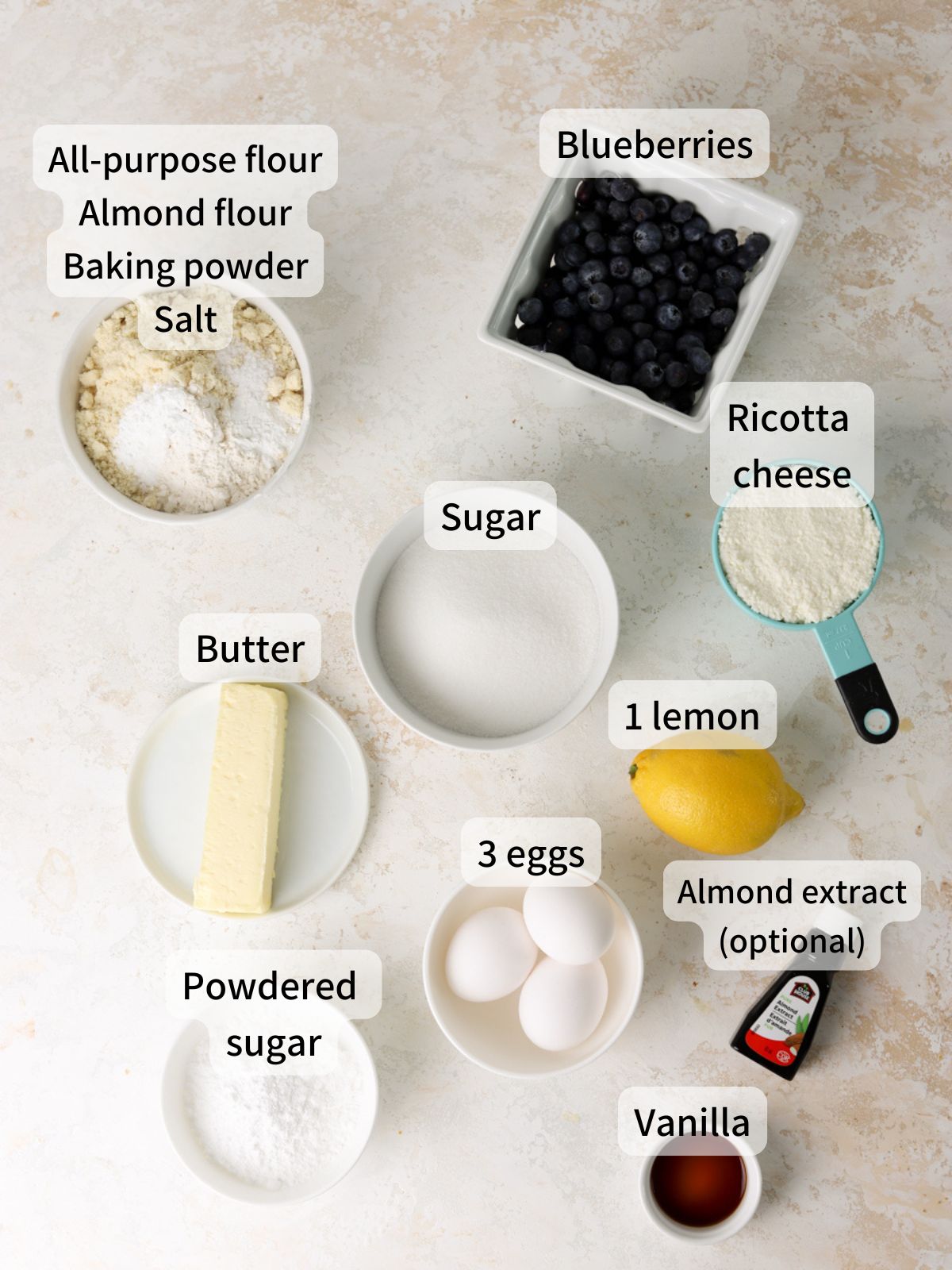 Labeled ingredients needed to make blueberry ricotta pound cake laid out on a table.