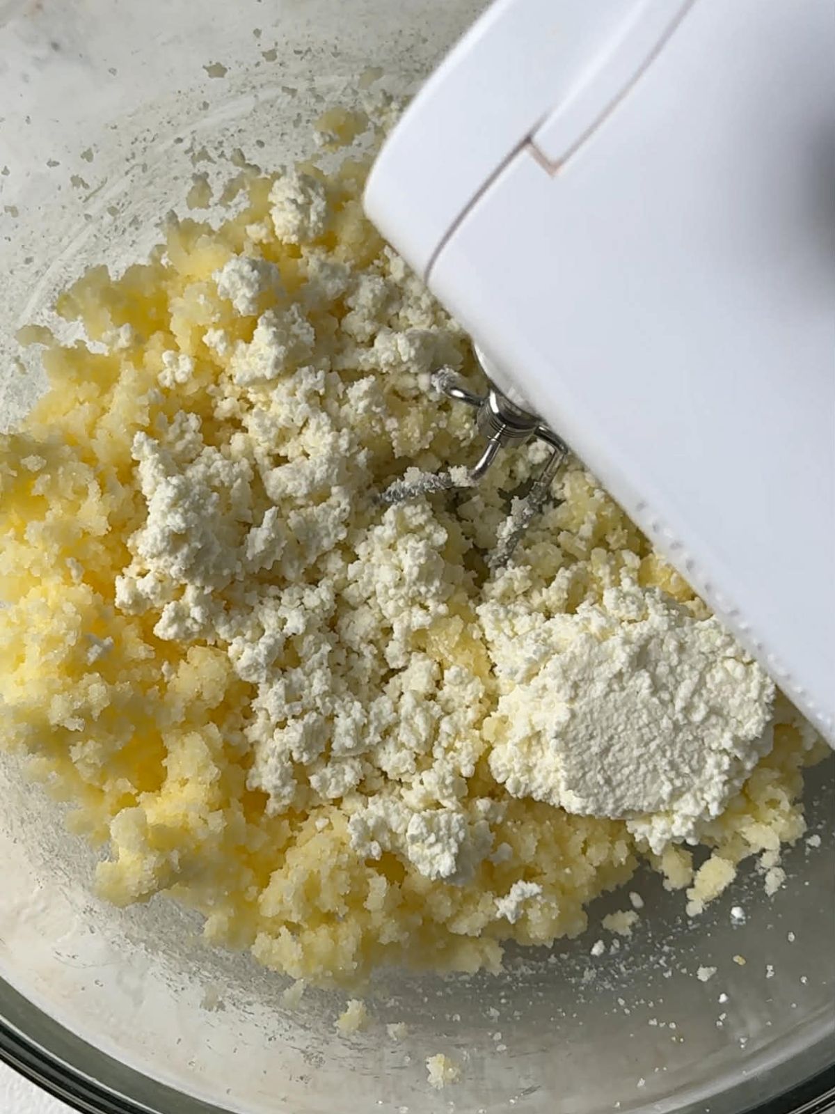 Ricotta cheese being mixed into sugar and butter.