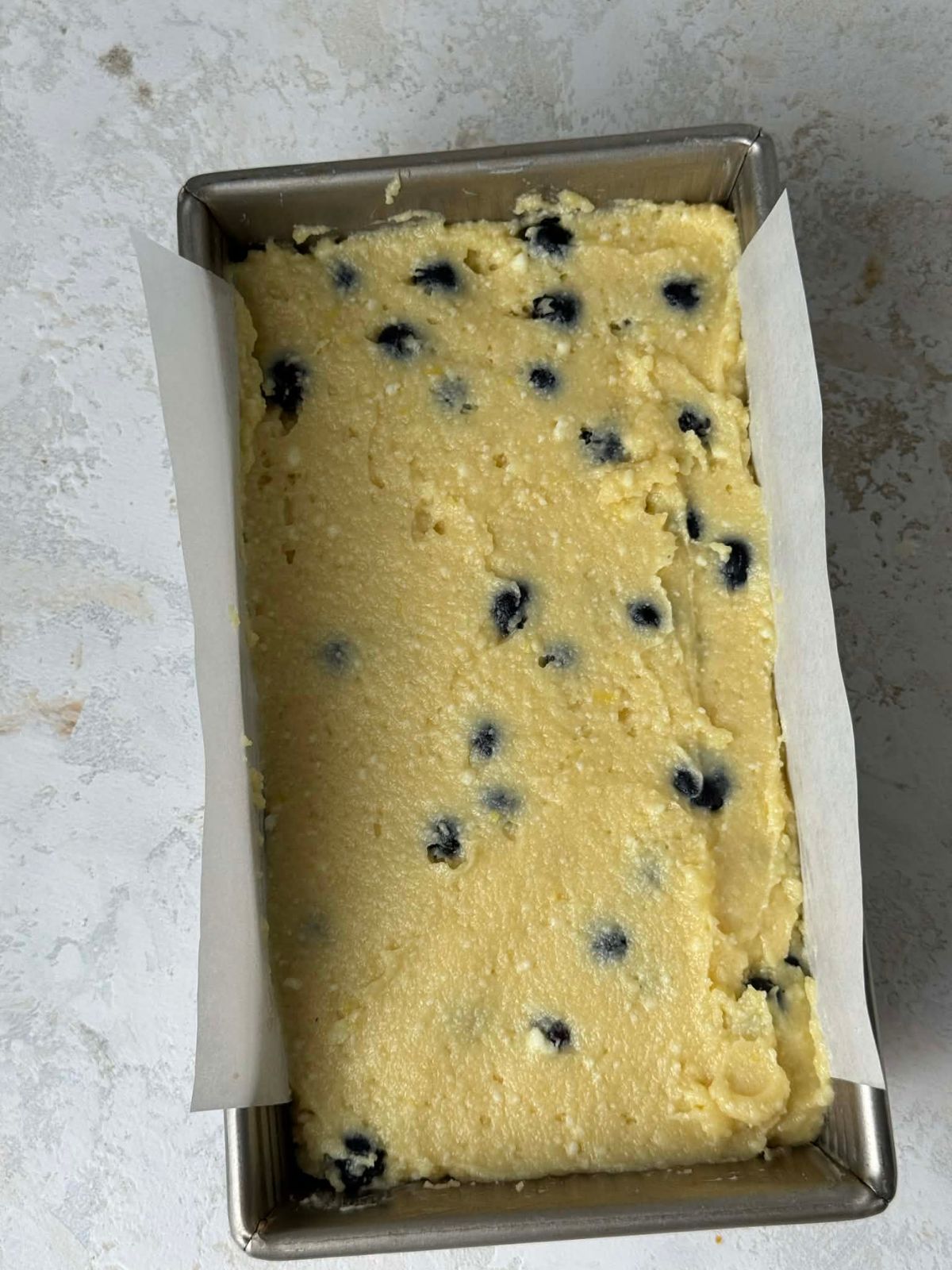 Blueberry filled loaf cake batter in a loaf pan.