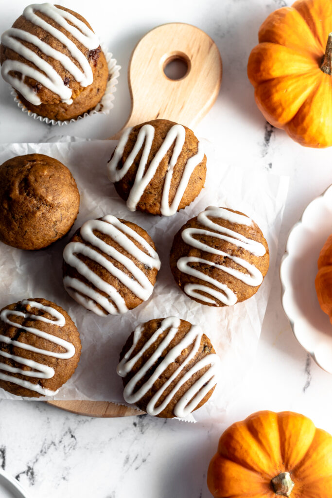 Pumpkin muffins drizzled with icing on a wooden board. 