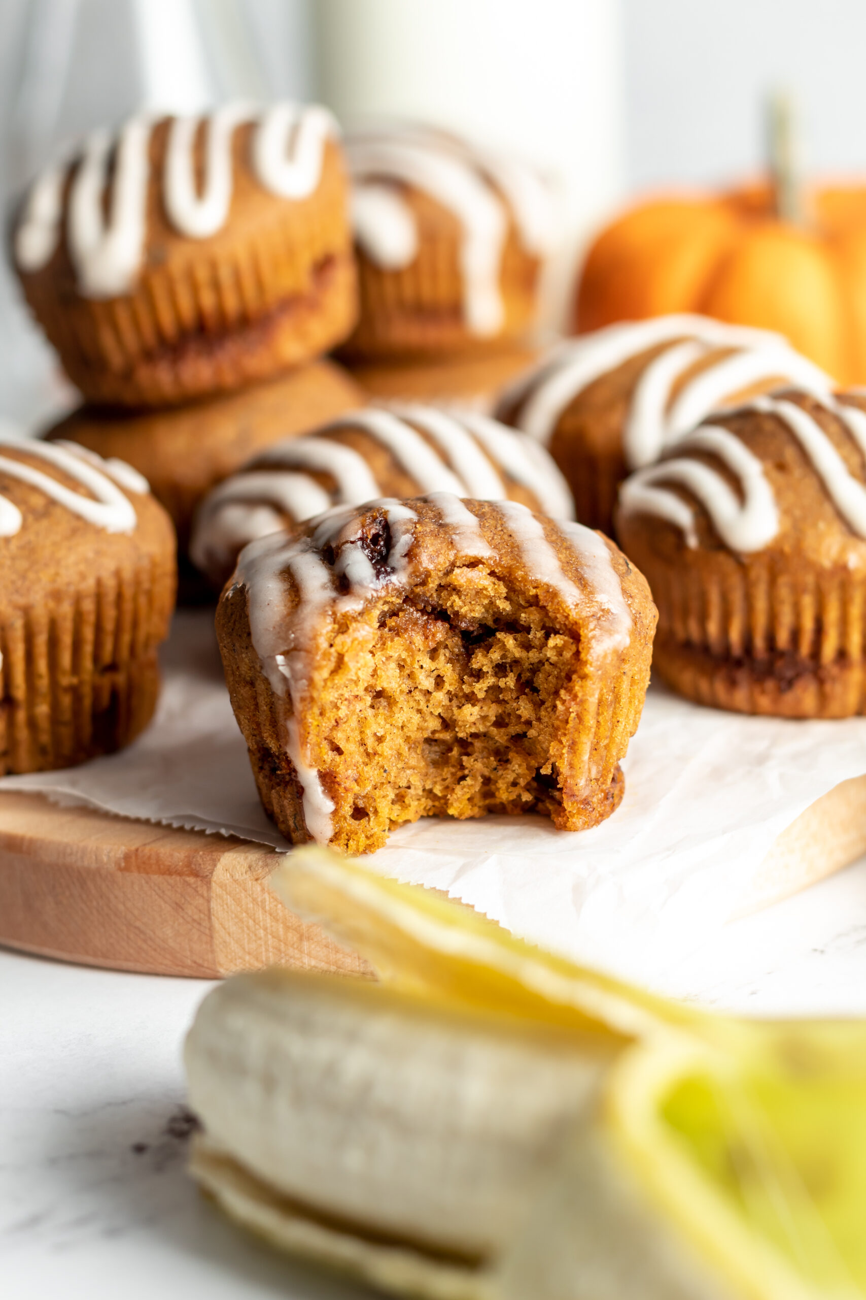 A pumpkin muffin with a bite in it next to a banana. 