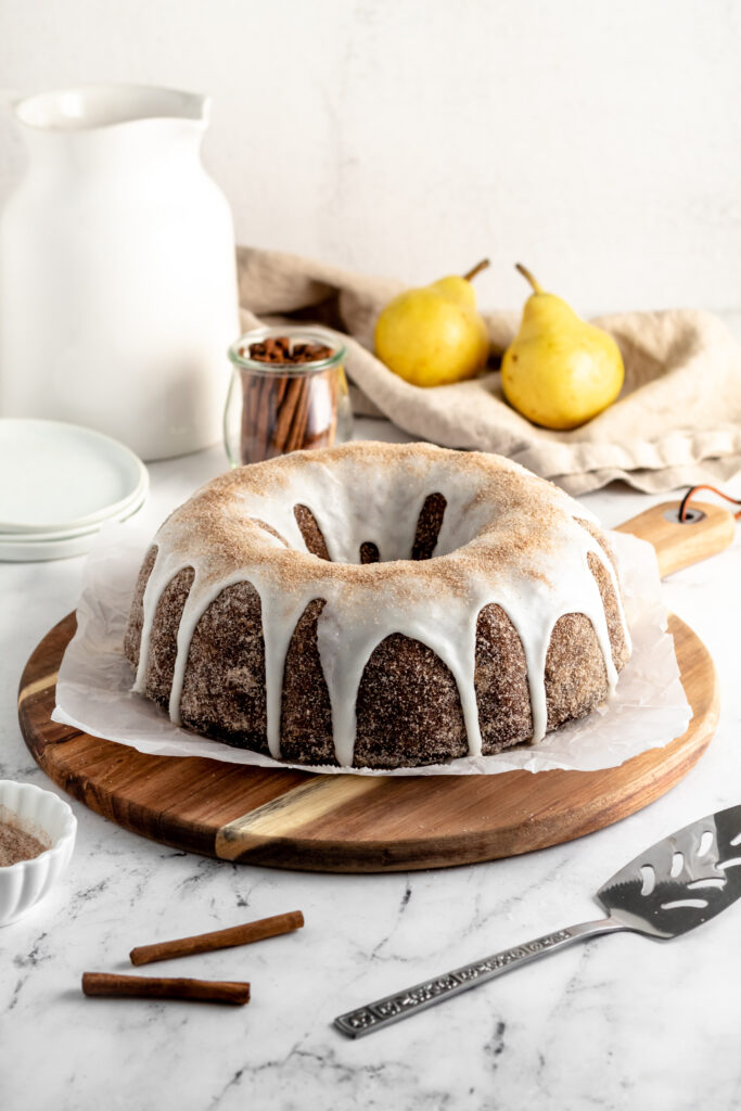 Chocolate and pear bundt cake on a piece of parchment paper and two pears. 