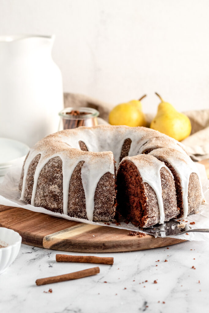 A chocolate bundt cake with icing and cinnamon sugar and some pears.