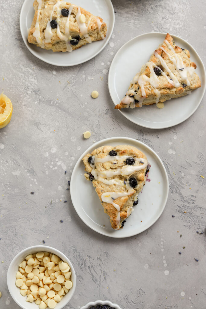Blueberry scones with lemon icing on white plates.