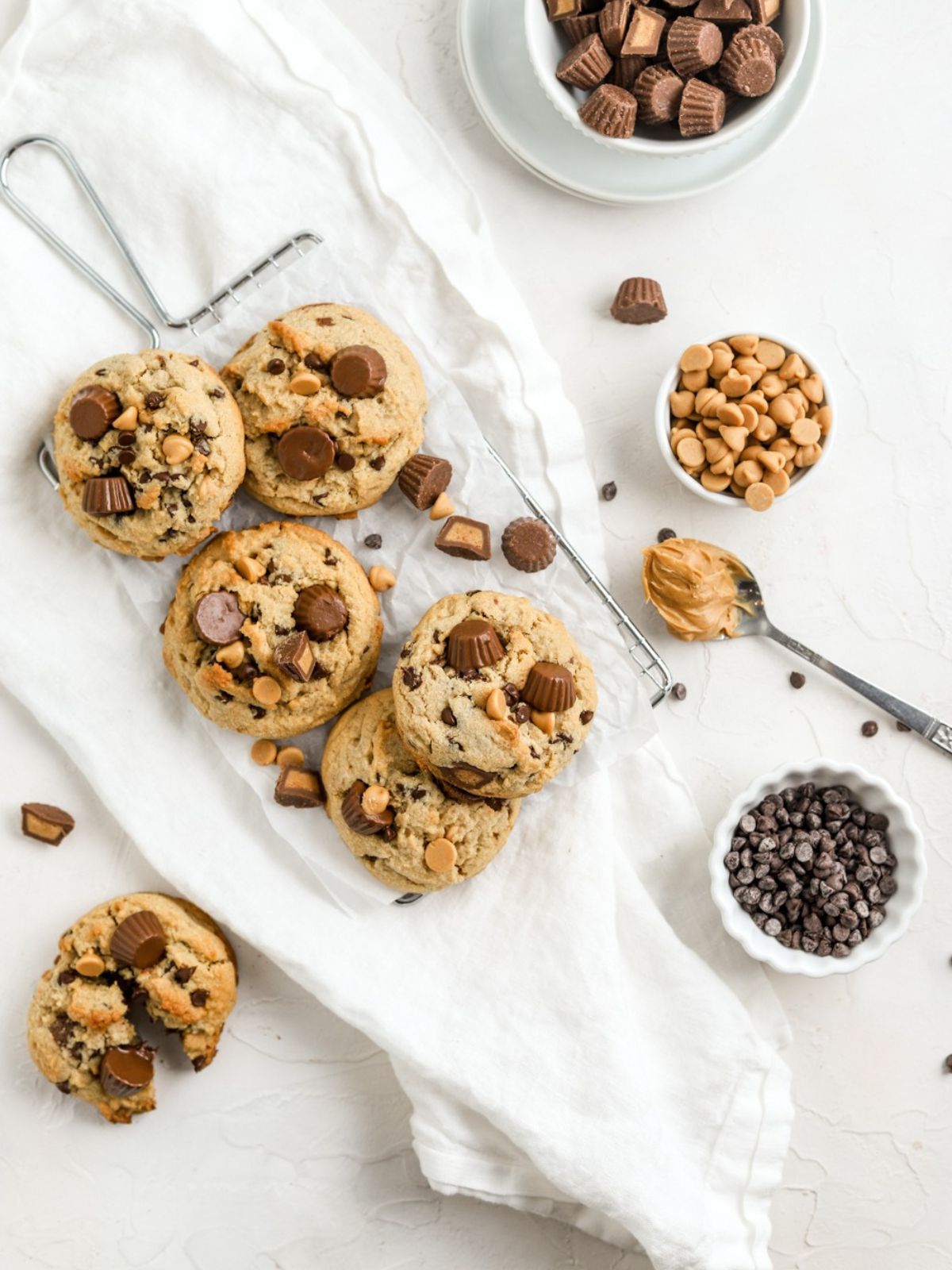 Peanut butter cookies on a rack with chocolate chips and a spoonful of peanut butter.