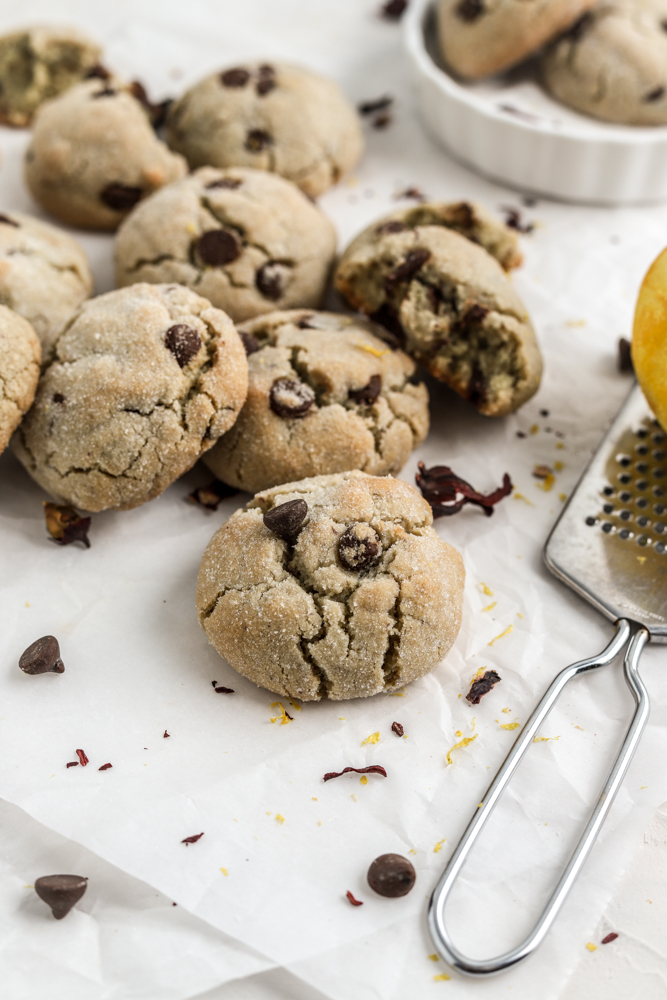 Chocolate chip sugar coated cookies with cracked tops next to a citrus zester. 