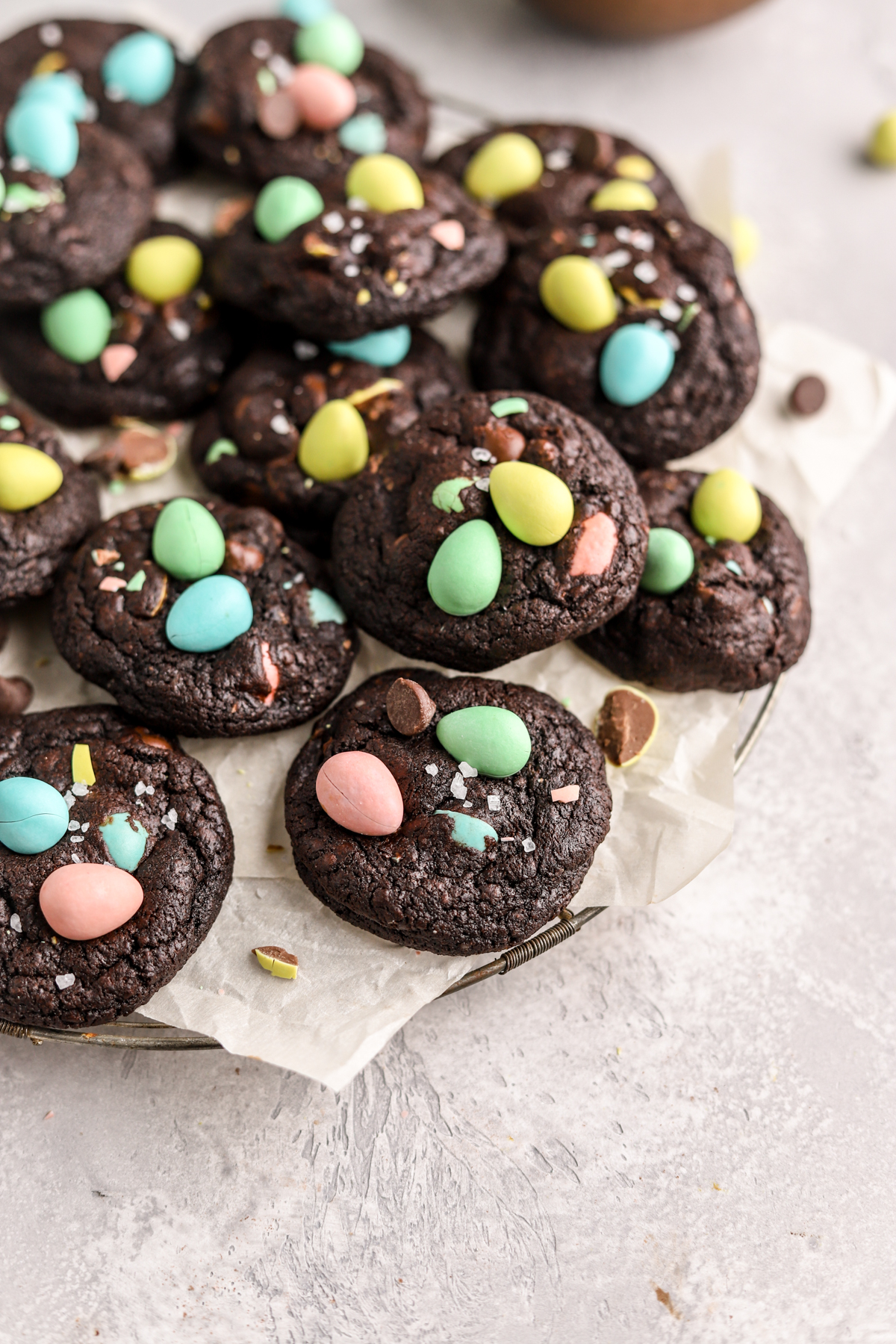 Chocolate cookies topped with mini eggs on a baking rack.