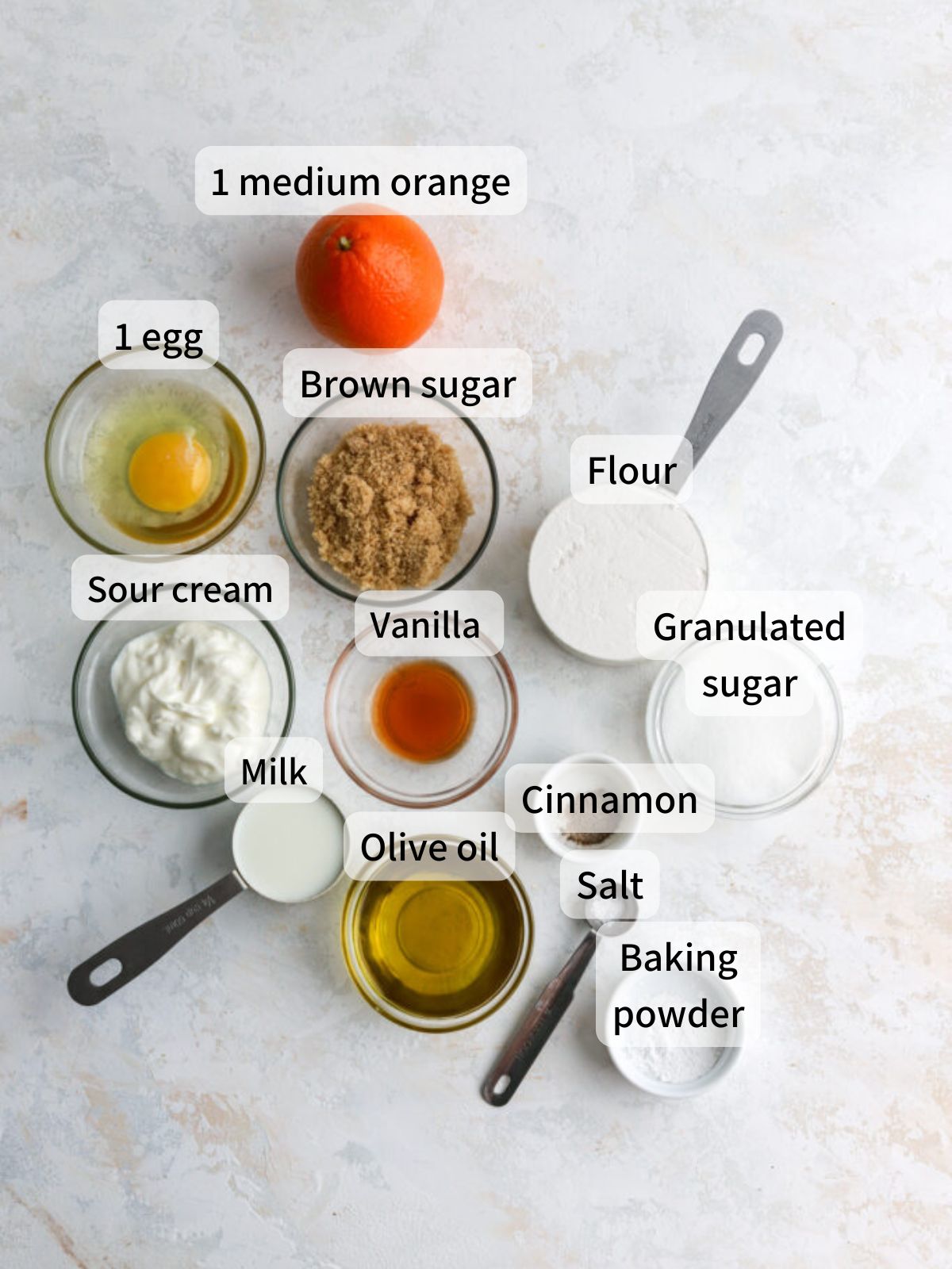 Labeled ingredients needed to make orange donuts laid out on a table.