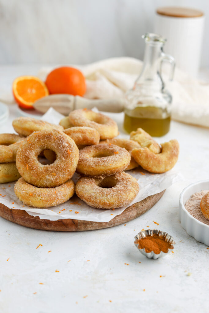 A batch of sugar coated donuts and a jug of olive oil. 