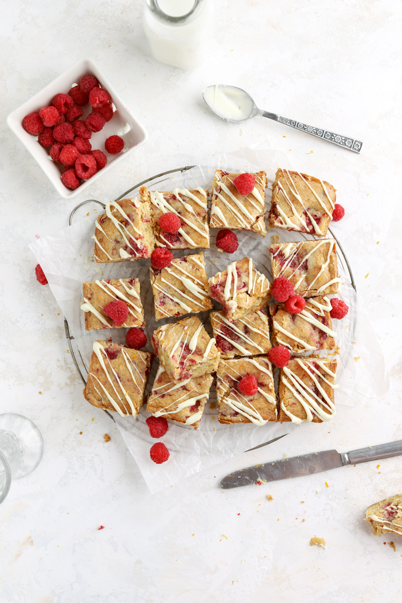 Raspberry blondies cut in squares on a cooling rack drizzled with chocolate. 