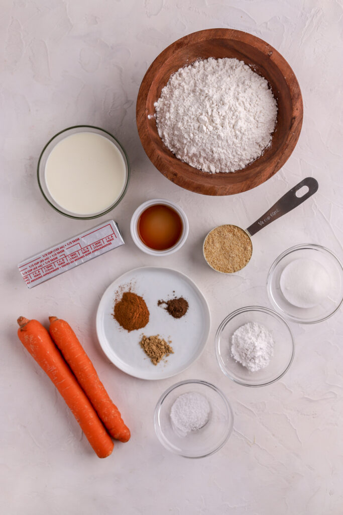 Ingredients in bowls and plates, a stick of butter and two carrots. 