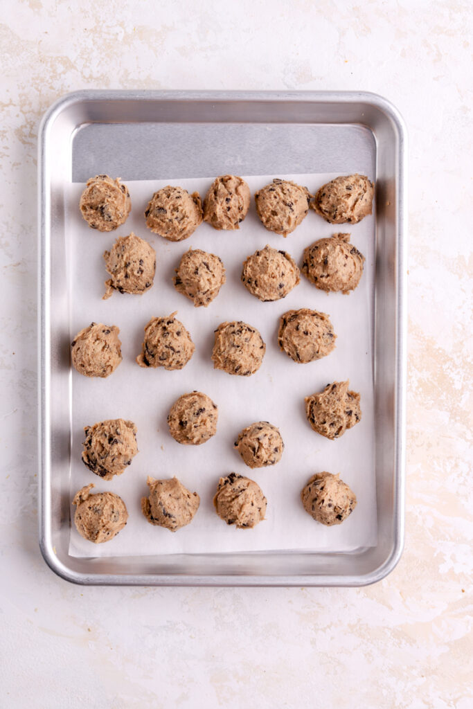 A small cookie sheet with chocolate chip cookie dough balls. 