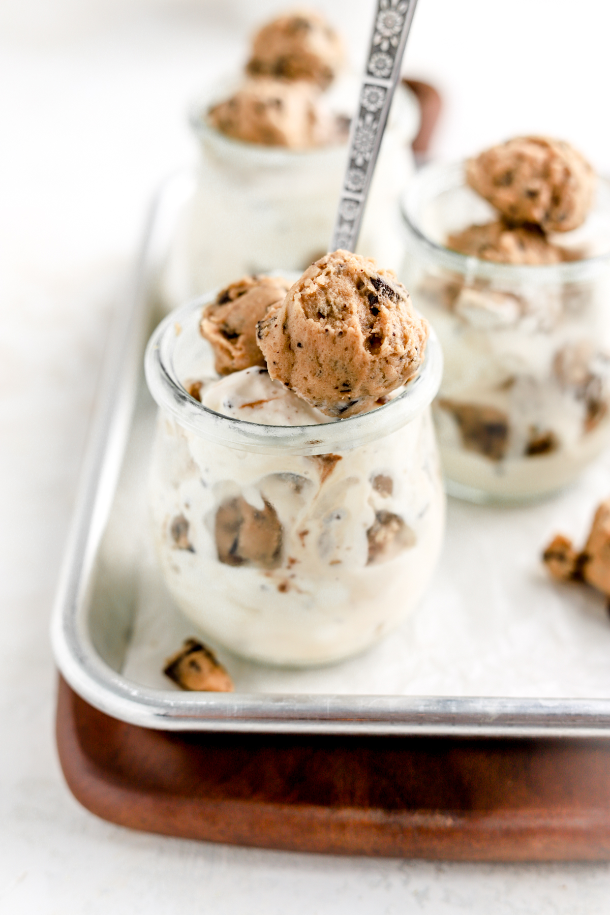 Jars of blizzards topped with cookie dough balls on a baking tray.
