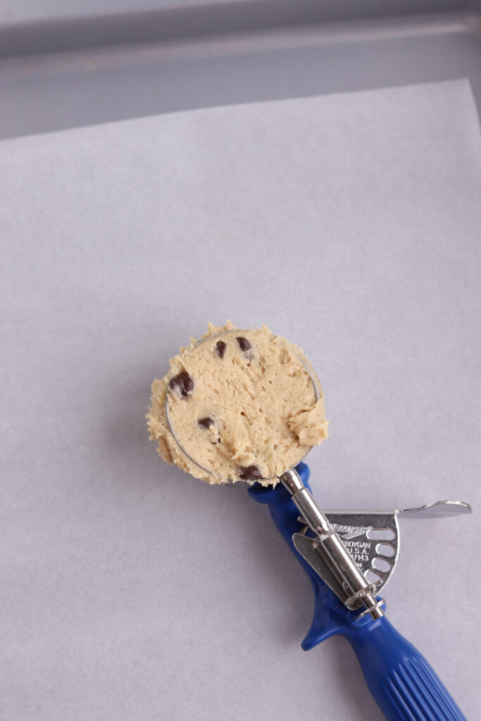 A blue ice cream scoop filled with chocolate chip cookie dough.