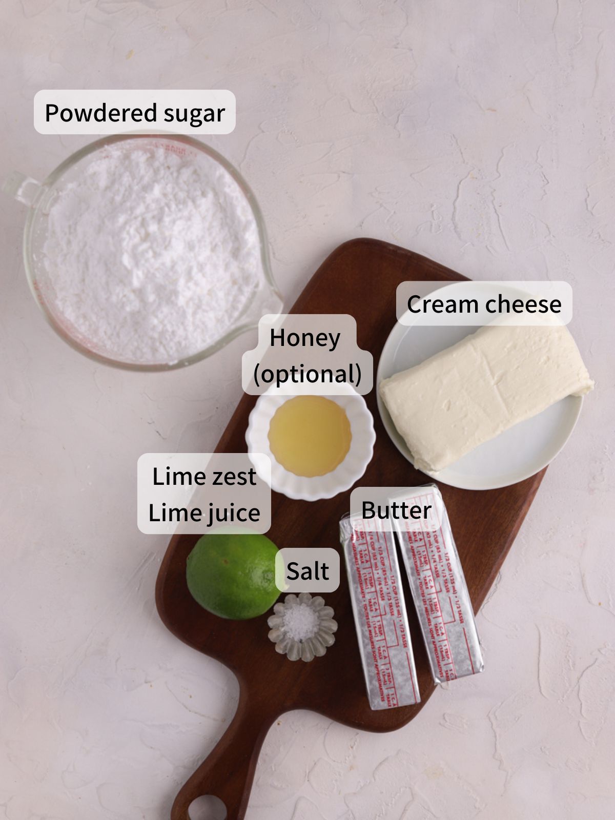 Labeled ingredients needed to make lime cream cheese frosting laid out on a table.