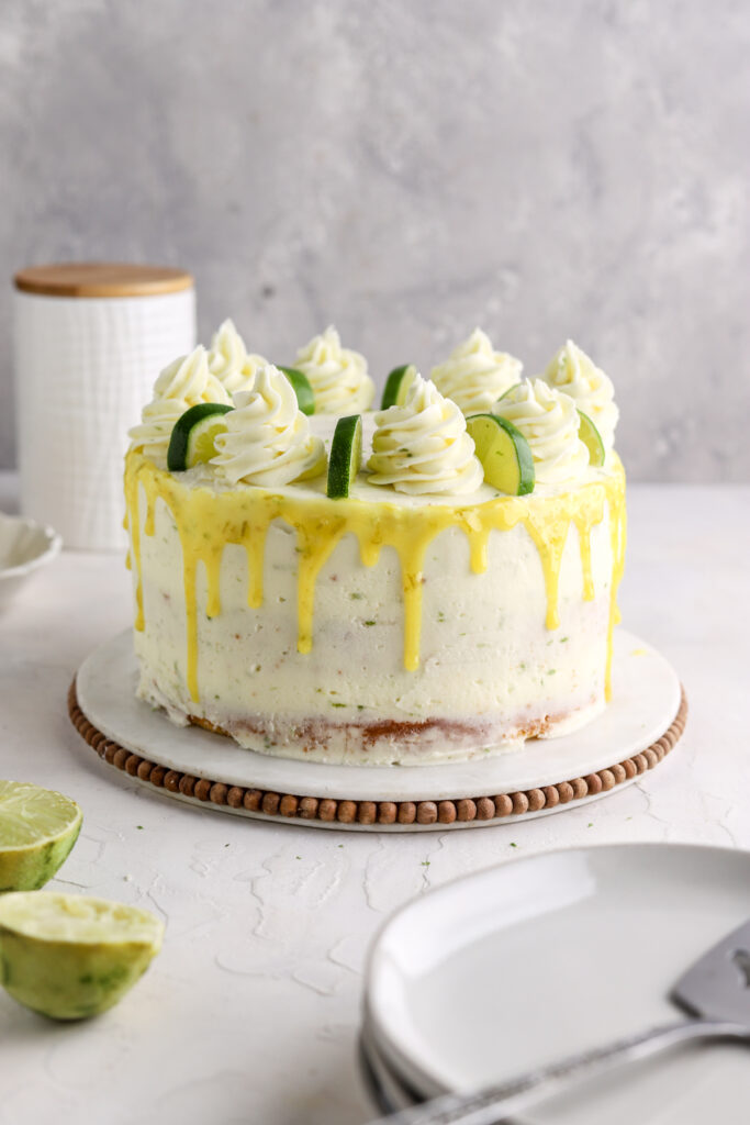 Lime cake on a cake stand with lime halves on top. 