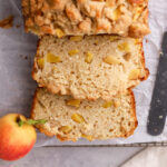 A peach cobbler pound cake loaf cut into slices and a fresh peach.