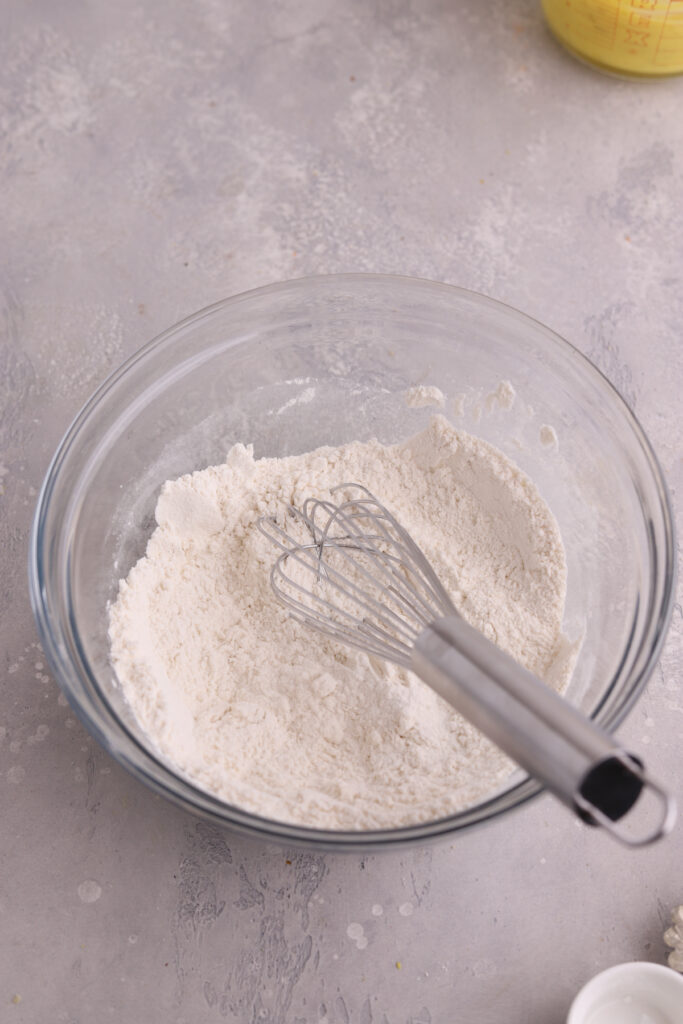 A bowl with flour and a whisk in it.