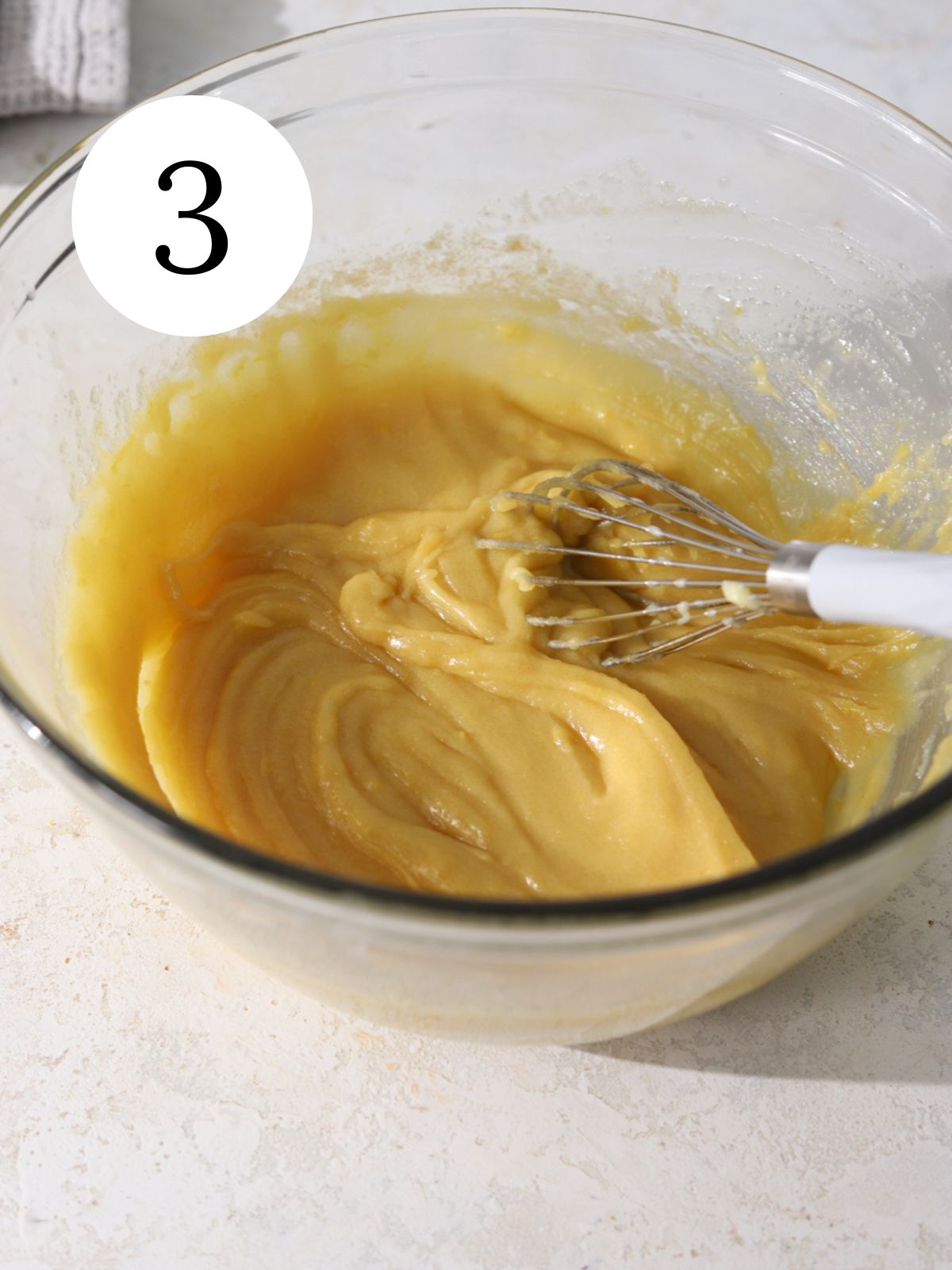 Butter and sugar mixed together with a whisk in a large glass bowl. 