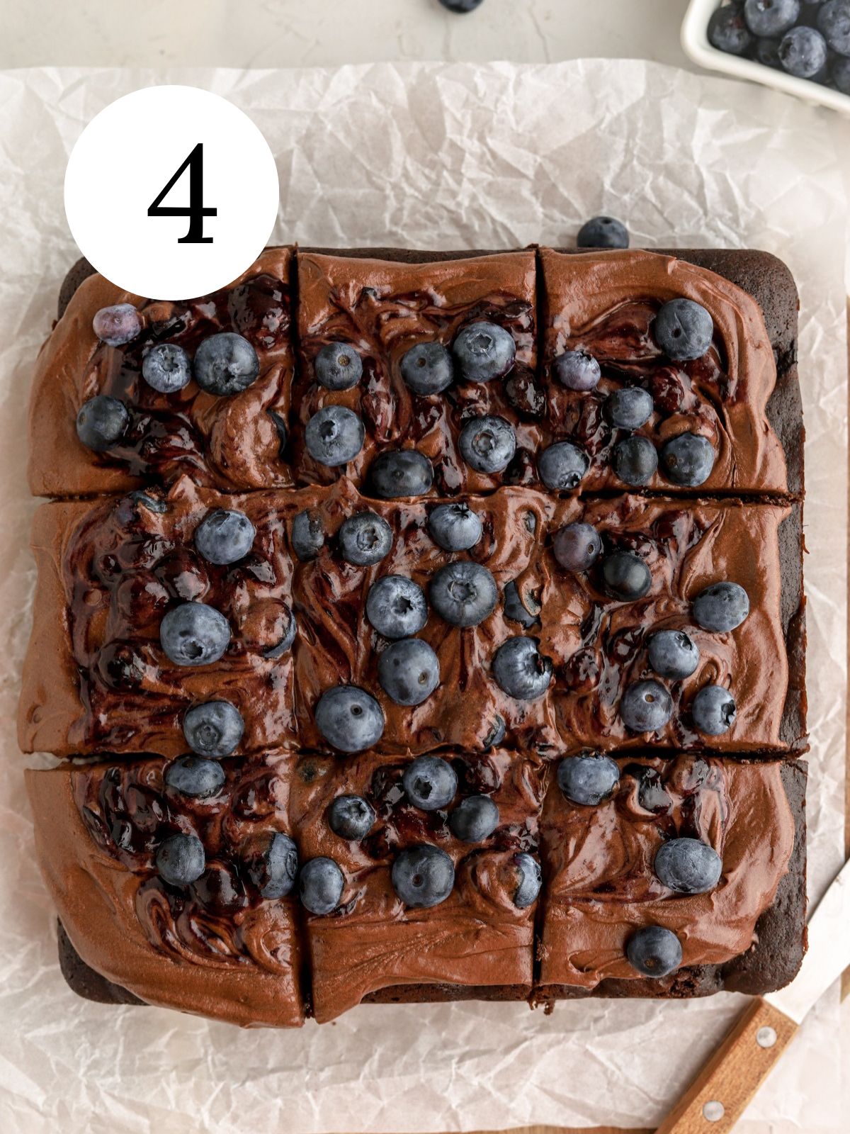 A square chocolate cake with chocolate frosting and blueberries.