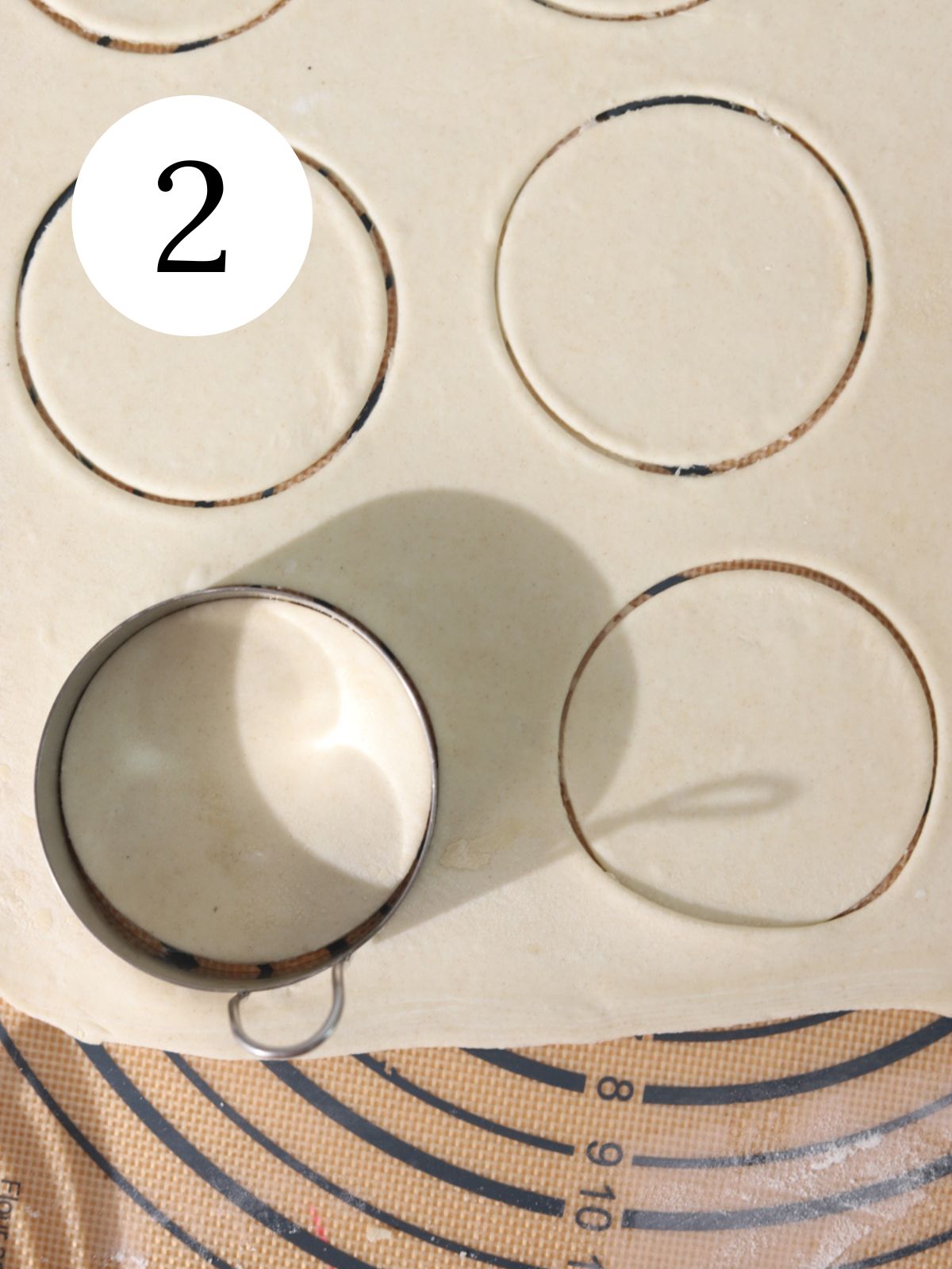 A sheet of puff pastry being cut in circles with a pastry cutter. 